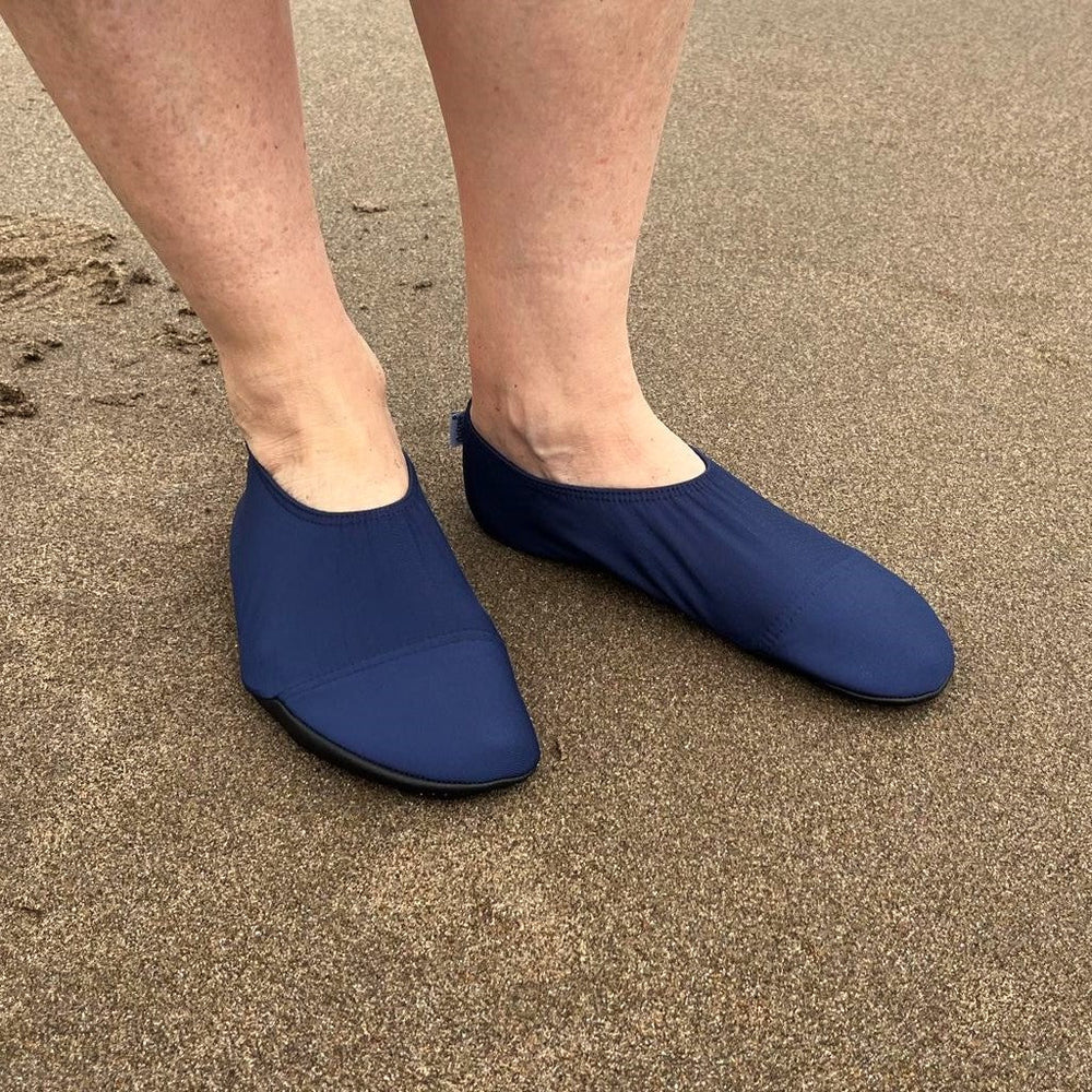 Lifestyle image of someone wearing navy swim shoes at the beach.