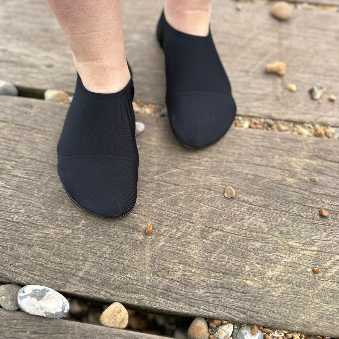 Lifestyle image of someone wearing black beach shoes.