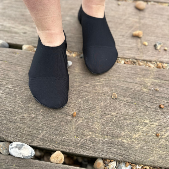 Lifestyle image of someone wearing black beach shoes.