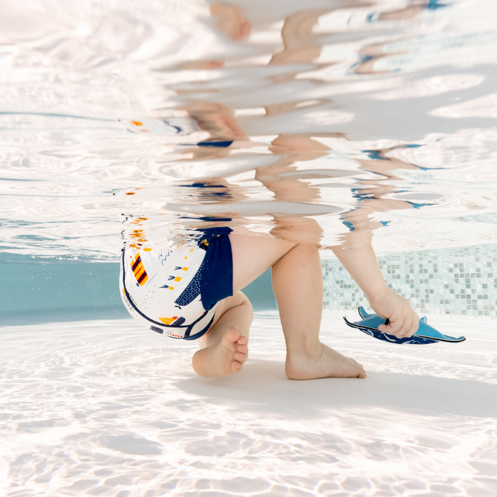 Lifestyle image of little one wearing swim nappy in the pool, side.