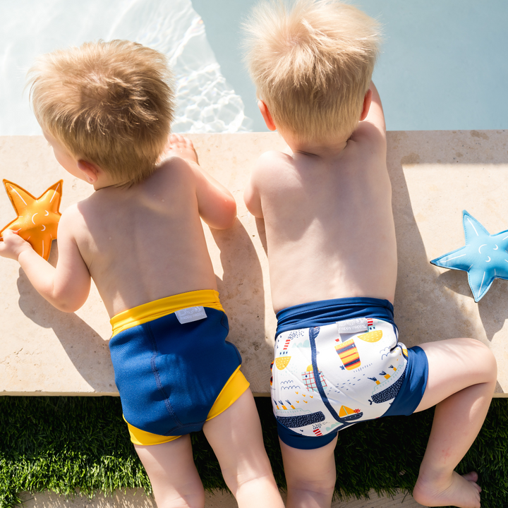 Lifestyle image of little ones wearing reusable swim nappies poolside, back.