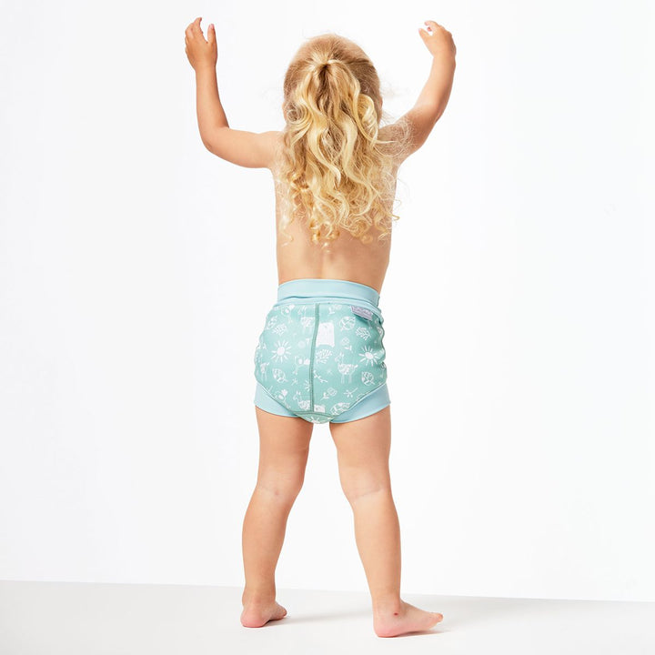 Lifestyle image of little one wearing swim nappy, standing up, back.