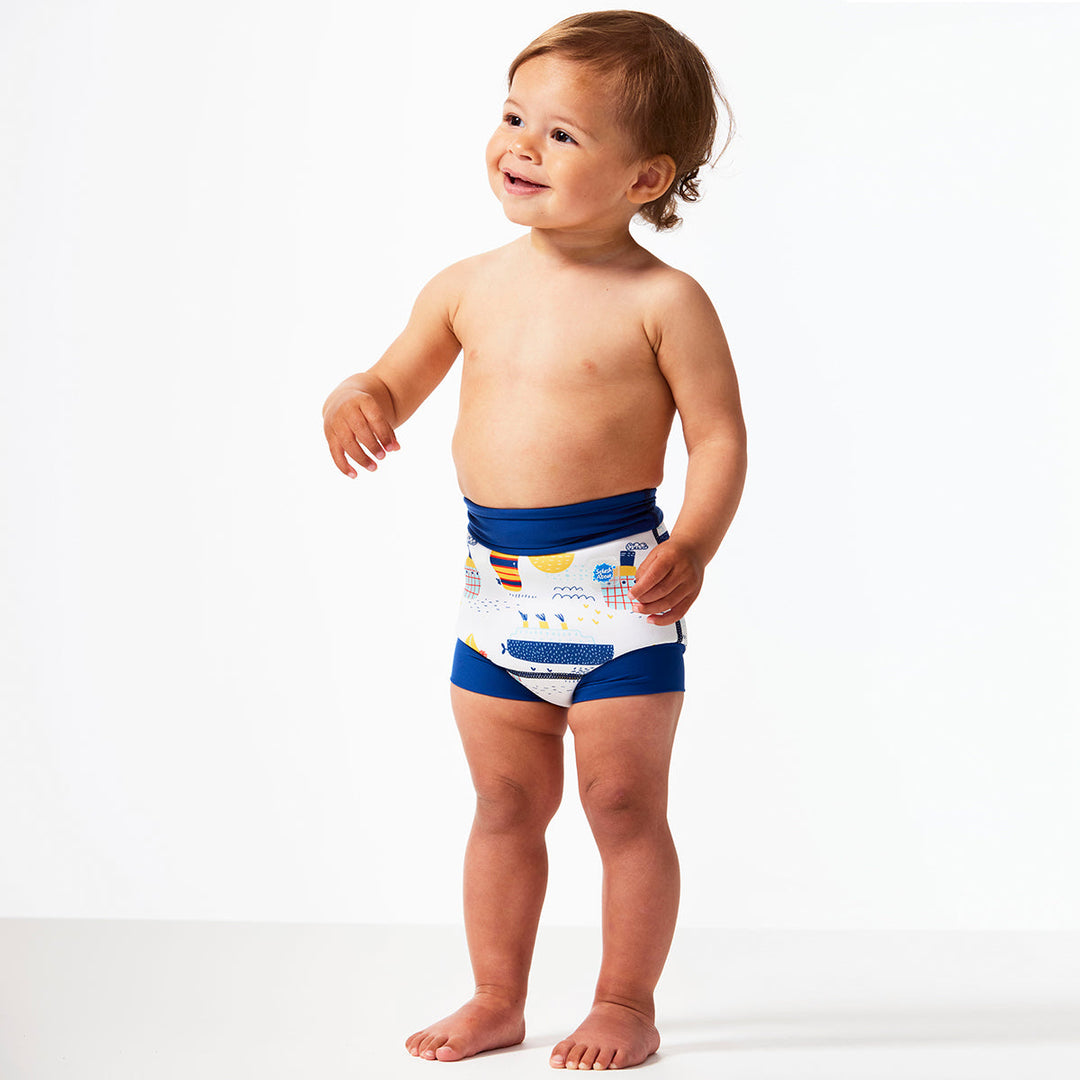 Little one wearing Happy Nappy in white with navy blue trims, featuring boats themed print. Side.