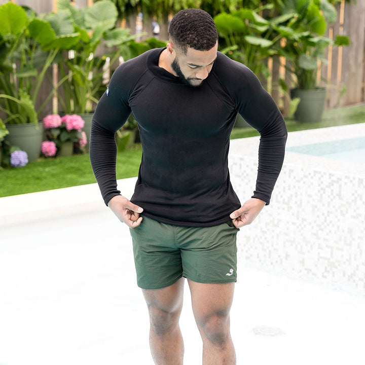Man wearing green swim shorts for men in green by the pool.