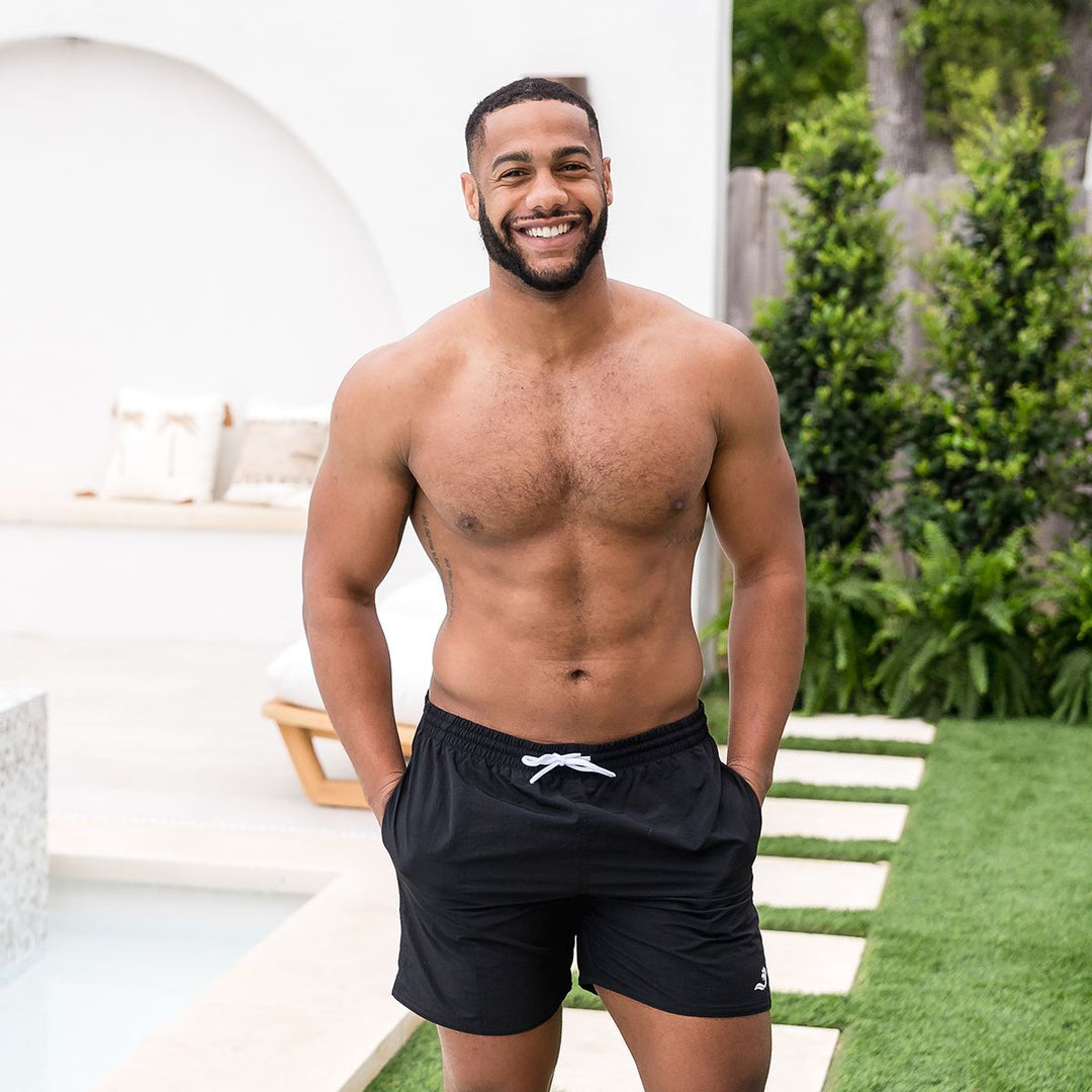 Man wearing black swim shorts for men in black by the pool.