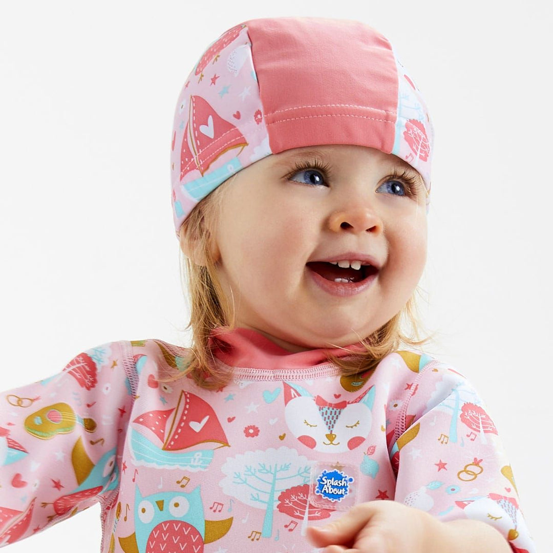Toddler wearing  swim hat in baby pink with pink trims and Owl & the Pussycat themed print.