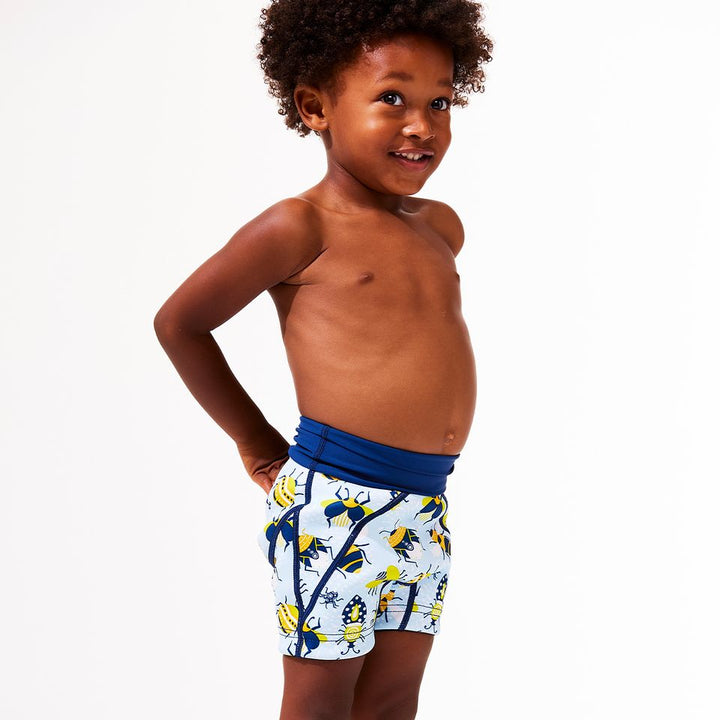 Lifestyle image of toddler wearing neoprene swim shorts in light blue with navy blue trims and insects print.