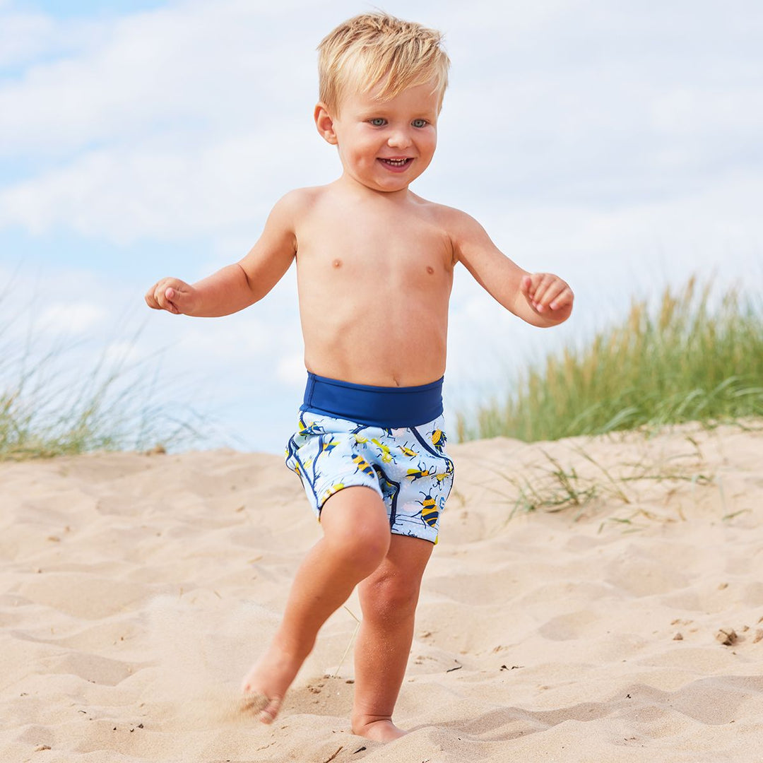 Lifestyle image of toddler wearing neoprene swim shorts in light blue with navy blue trims and insects print.
