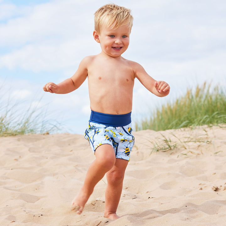 Lifestyle image of toddler wearing neoprene swim shorts in light blue with navy blue trims and insects print.