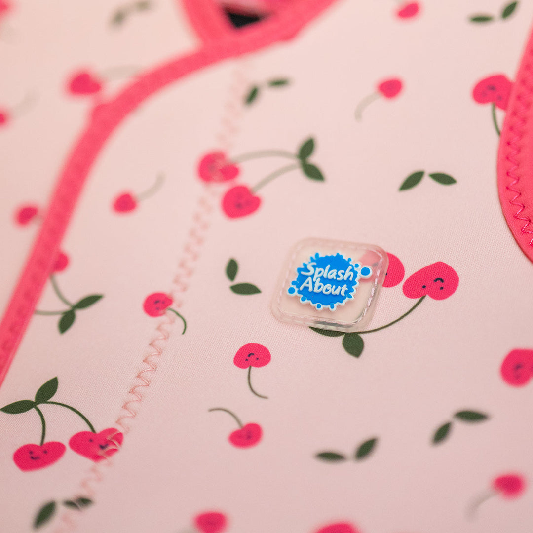 Close up of neoprene baby wrap wetsuit in pink and cherries themed print.