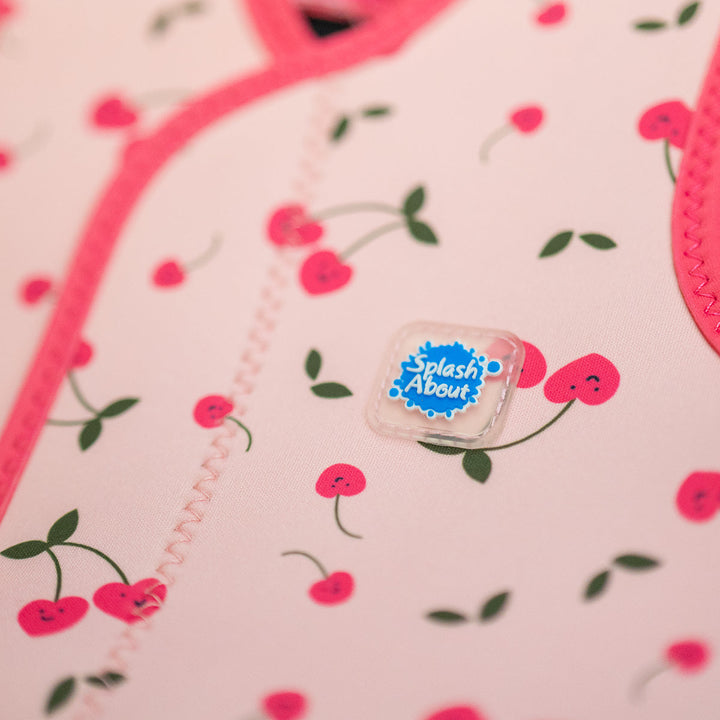 Close up of neoprene baby wrap wetsuit in pink and cherries themed print.