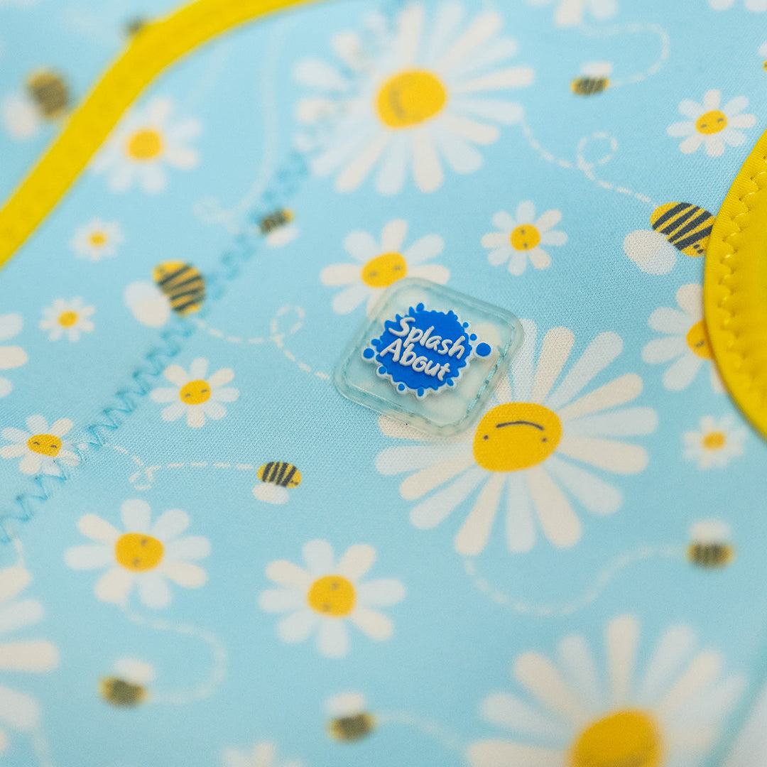 Close up of neoprene baby wrap wetsuit in baby blue with yellow trims and daisies and bees themed print.