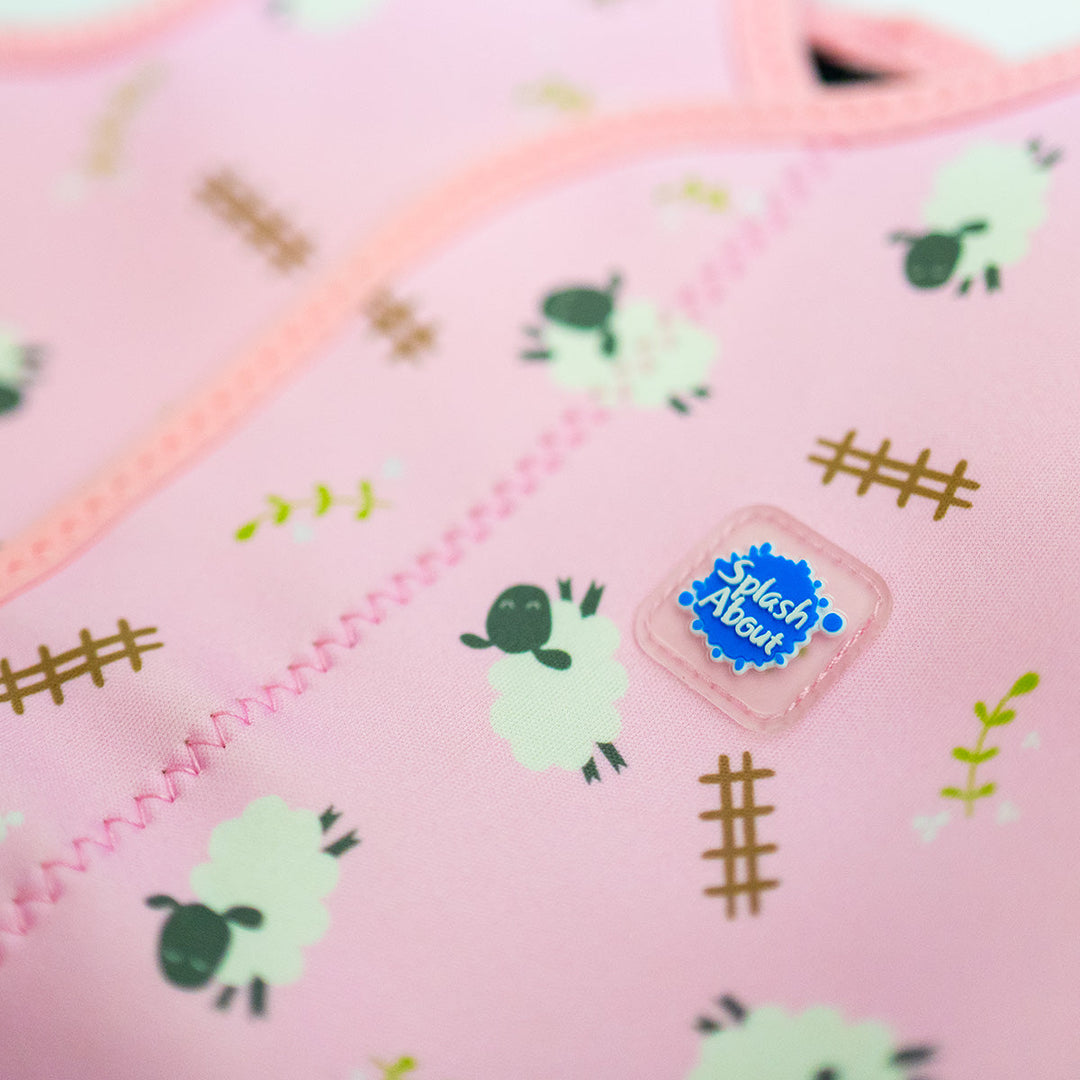 Close up of neoprene baby wrap wetsuit in baby pink and sheep themed print.