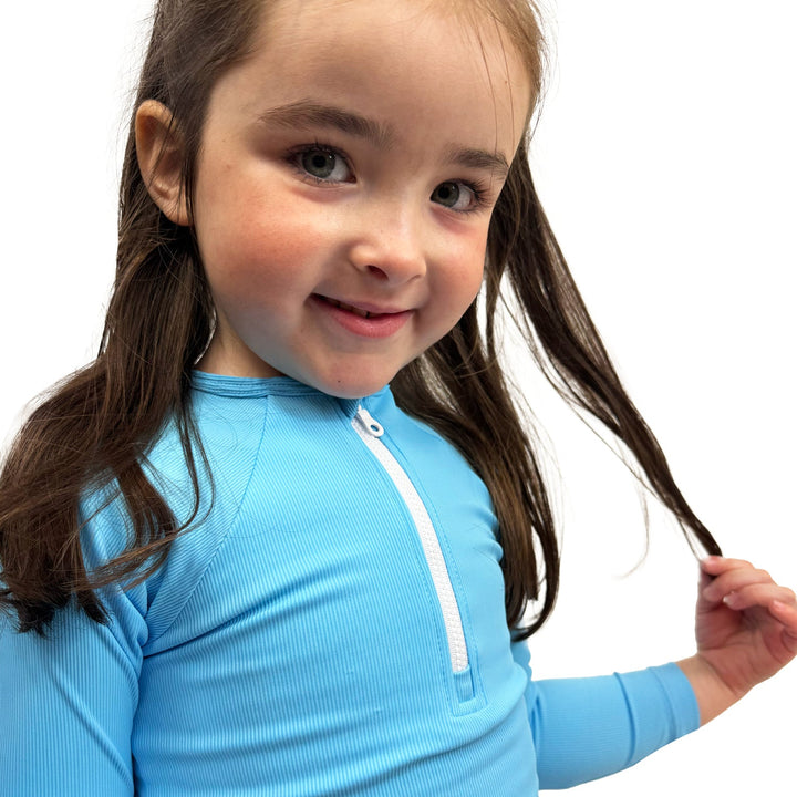 Little one wearing UV protective long sleeve rash top in neon blue.