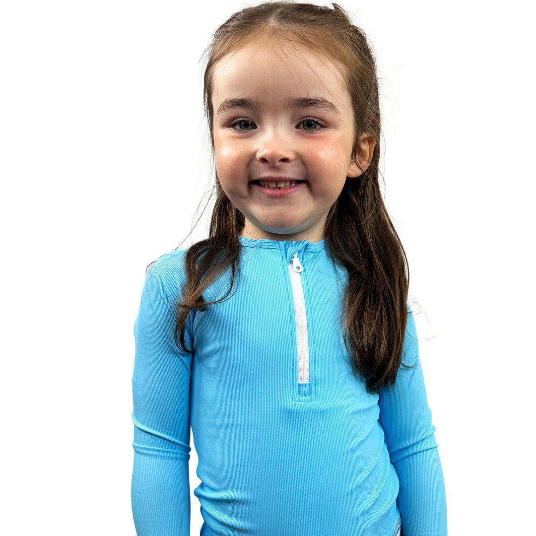 Little one wearing UV protective long sleeve rash top in neon blue.