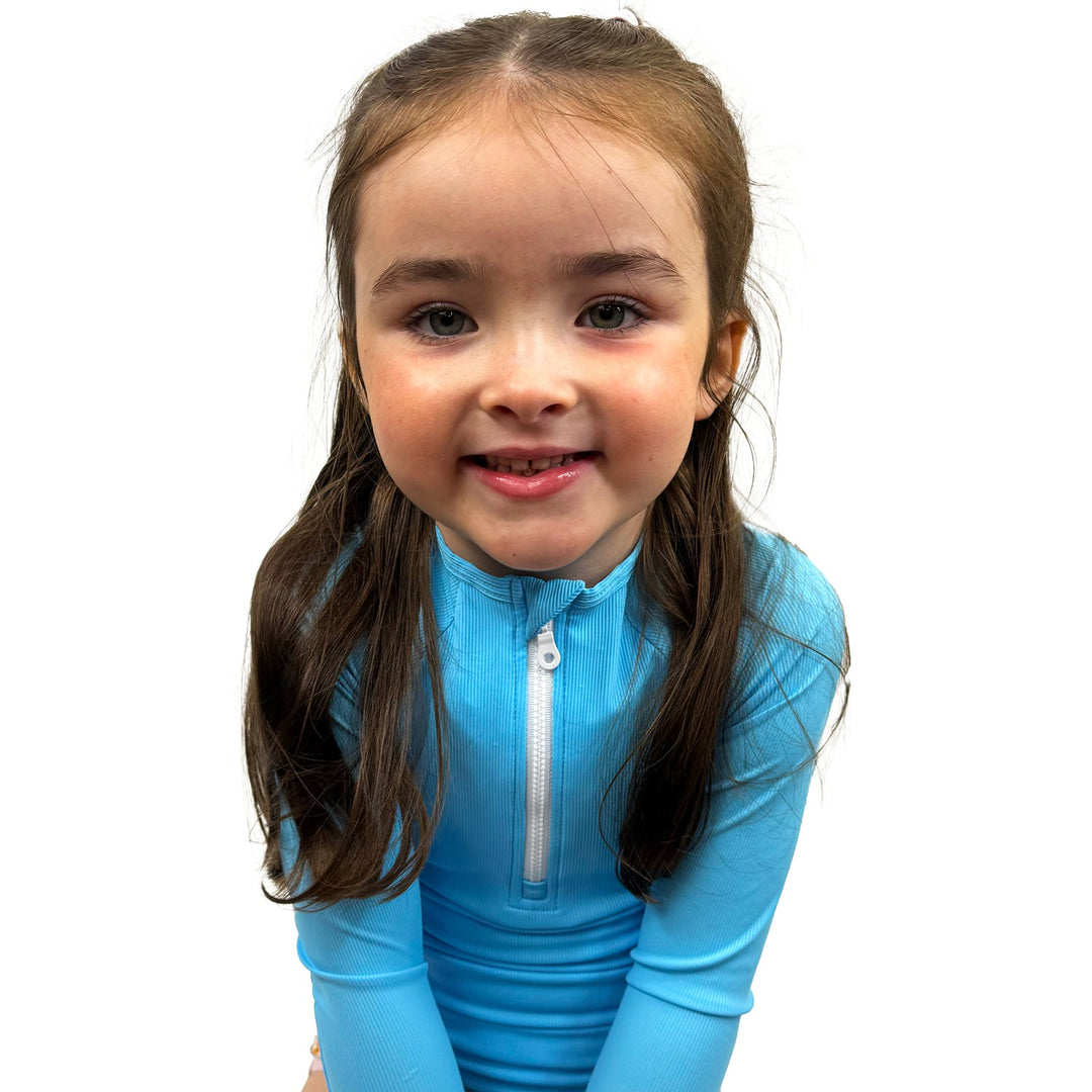 Little one wearing UV protective long sleeve rash top in neon blue.