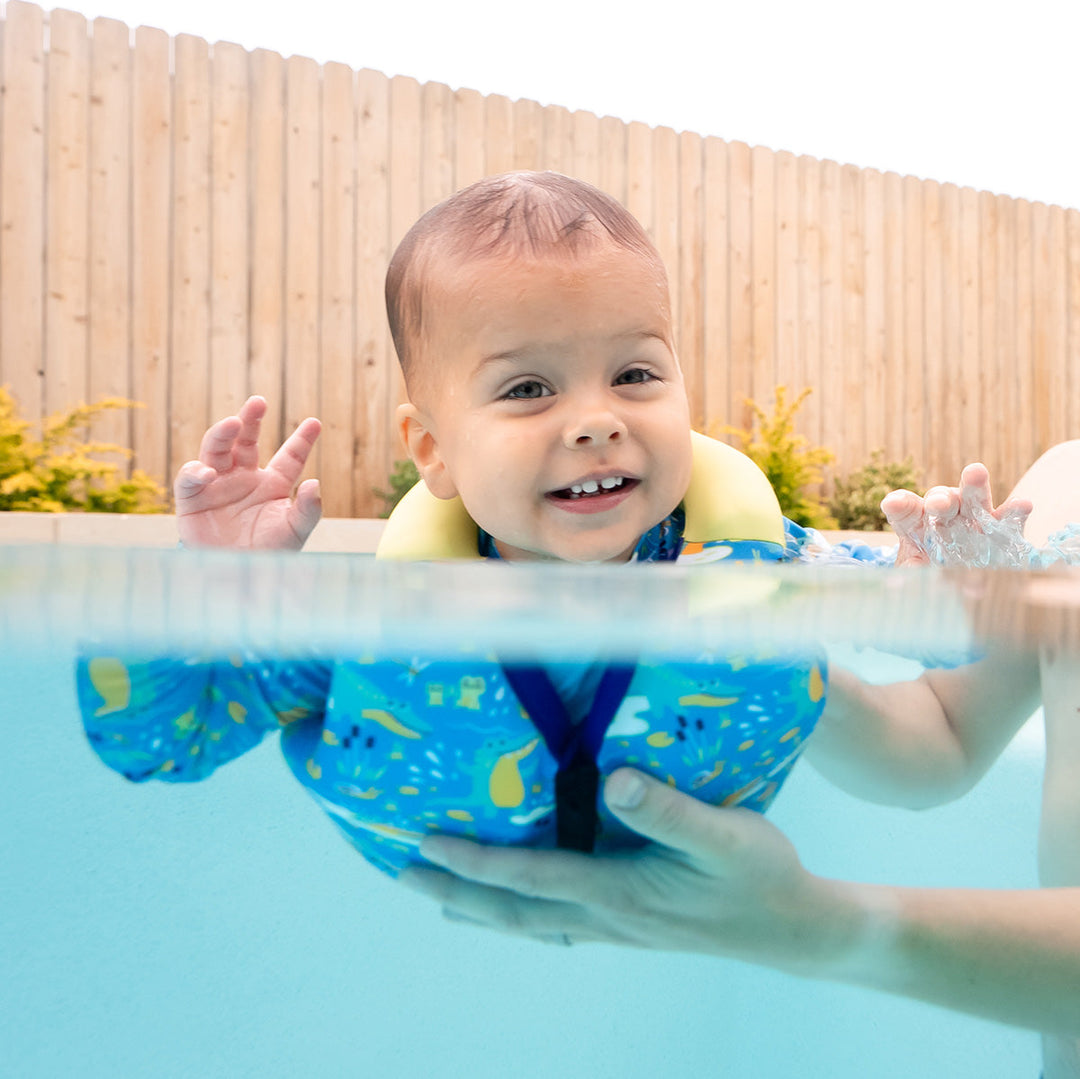 Little one in the pool, wearing swim vest with crocodile print, front zip and bright trim for kids learn to swim