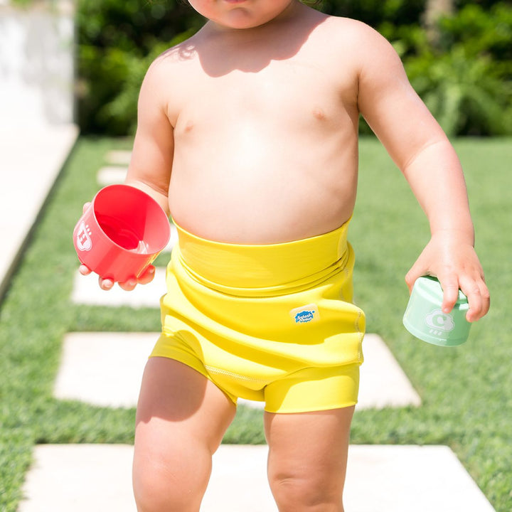 Close up of little one wearing neoprene swim nappy in bright yellow, front.