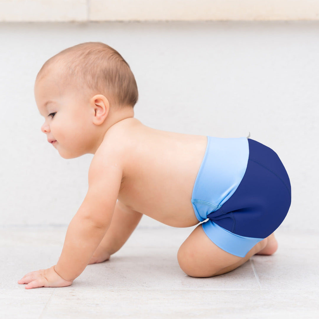 Little one wearing neoprene swim nappy in navy with blue ribs.