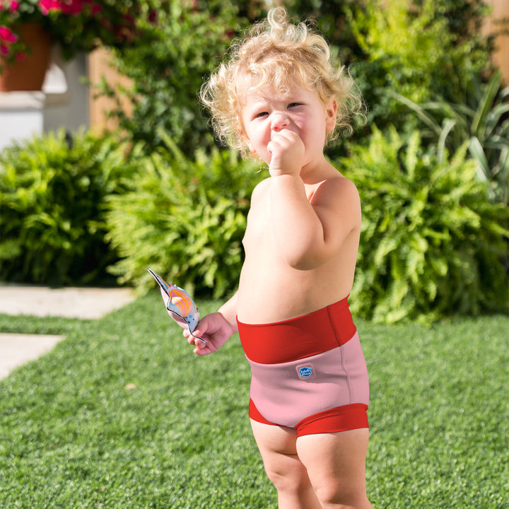 Little one wearing neoprene swim nappy in pink with red ribs.