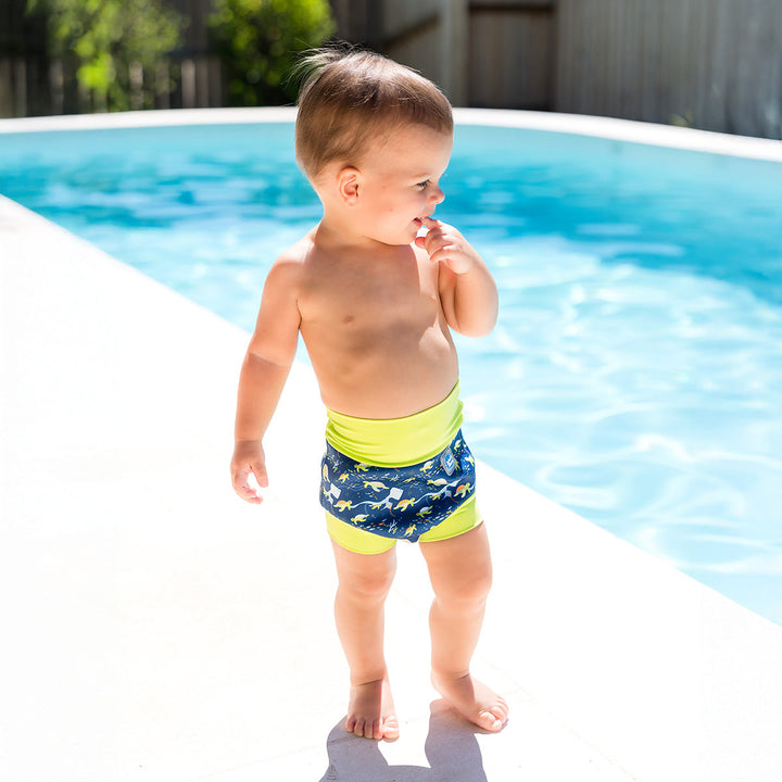 Little one wearing neoprene swim nappy in navy, with lime ribs and turtles themed print.