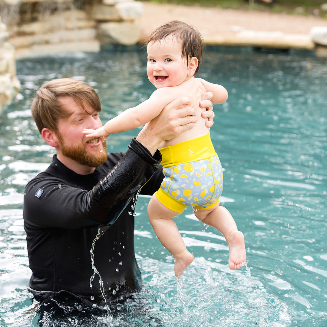 Little one wearing neoprene swim nappy in blue, with yellow ribs and lemons themed print.