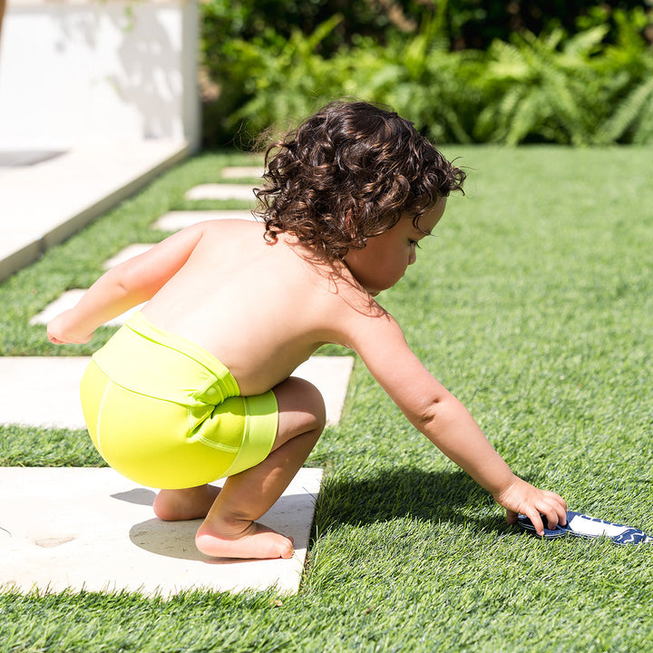 Little one swimming in neoprene swim nappy in bright lime green.