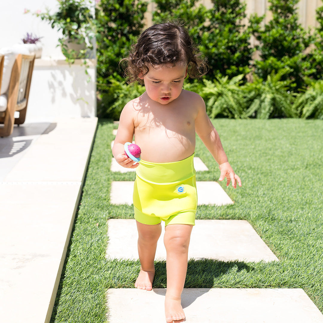 Little one wearing neoprene swim nappy in bright lime green, poolside.