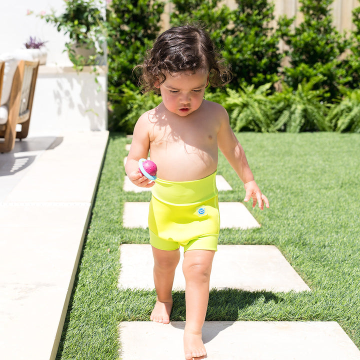 Little one wearing neoprene swim nappy in bright lime green, poolside.