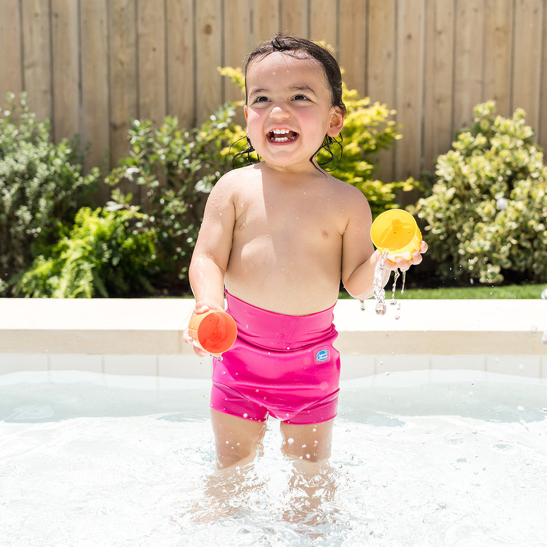 Little one wearing neoprene swim nappy in hot pink, playing in the pool.