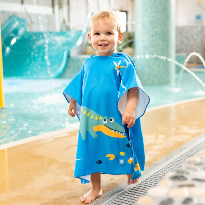Little one wearing poncho towel in blue with crocodiles and frogs themed print.