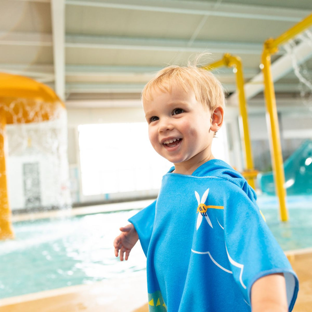 Little one wearing poncho towel in blue with crocodiles and frogs themed print.