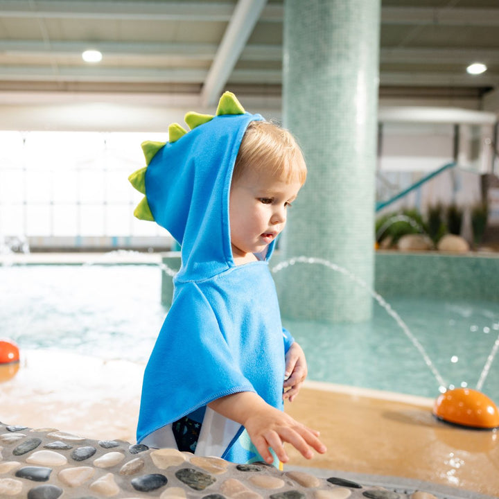 Little one wearing poncho towel in blue with crocodiles and frogs themed print.