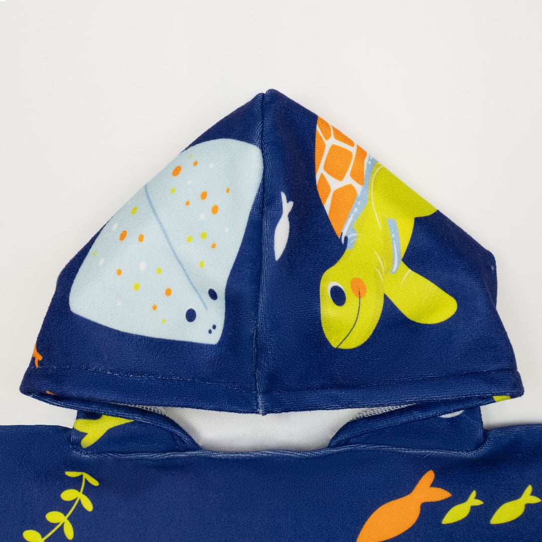 Flat lay image of poncho towel in navy with turtles and sea creatures themed print. Close up of the hood.