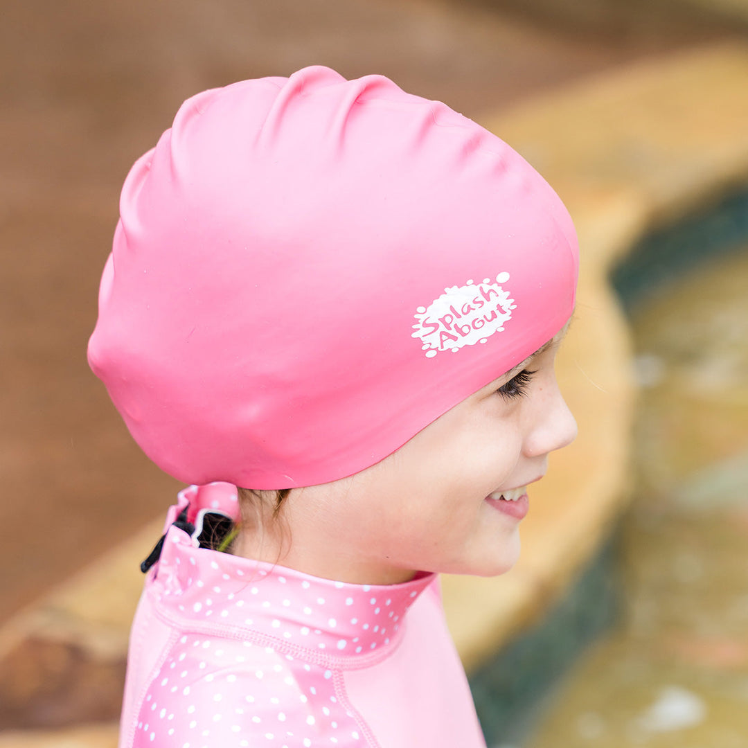 Close-up of kid wearing pink silicone swim cap, side.