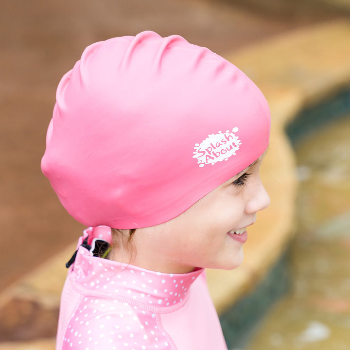 Close-up of kid wearing pink silicone swim cap, side.