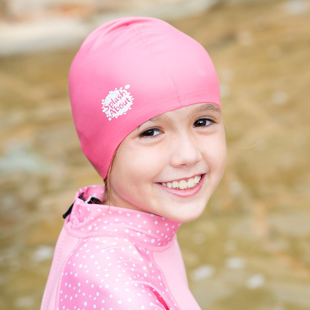 Close-up of kid wearing pink silicone swim cap, front.