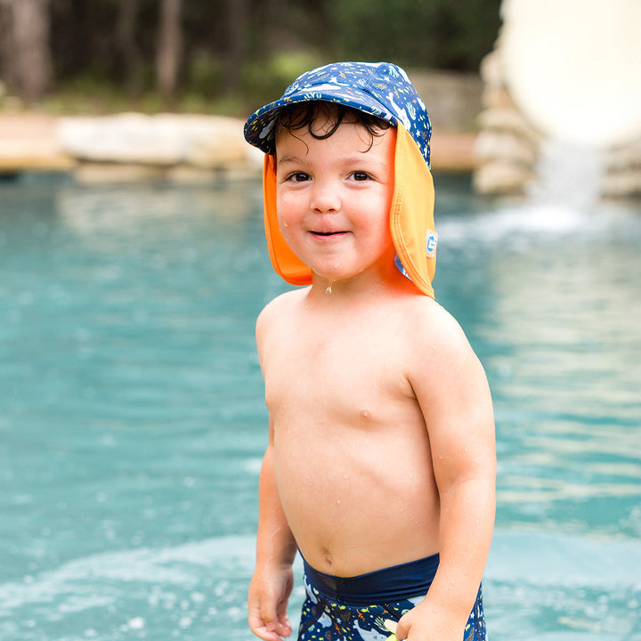 Little one wearing legionnaire style sun hat in navy and orange, with sharks themed print panel.