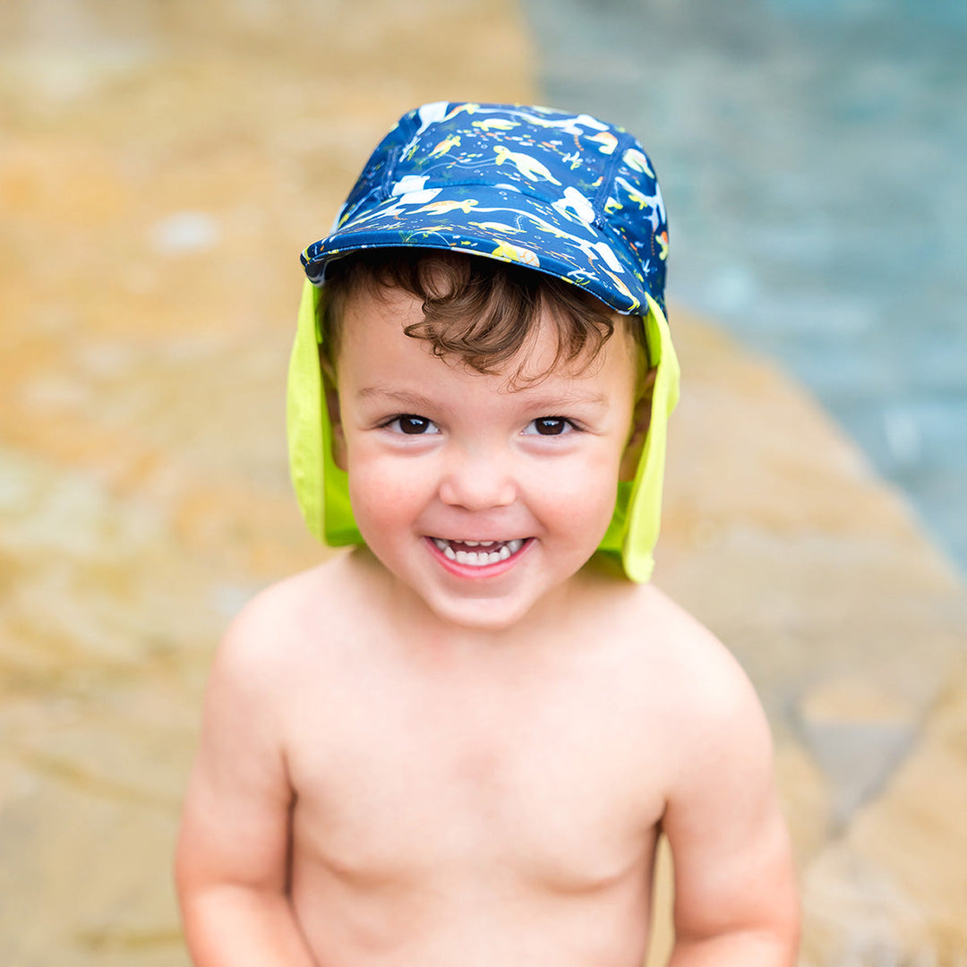 Little one wearing legionnaire style sun hat in navy and lime, with turtles and mantarays themed print panel.