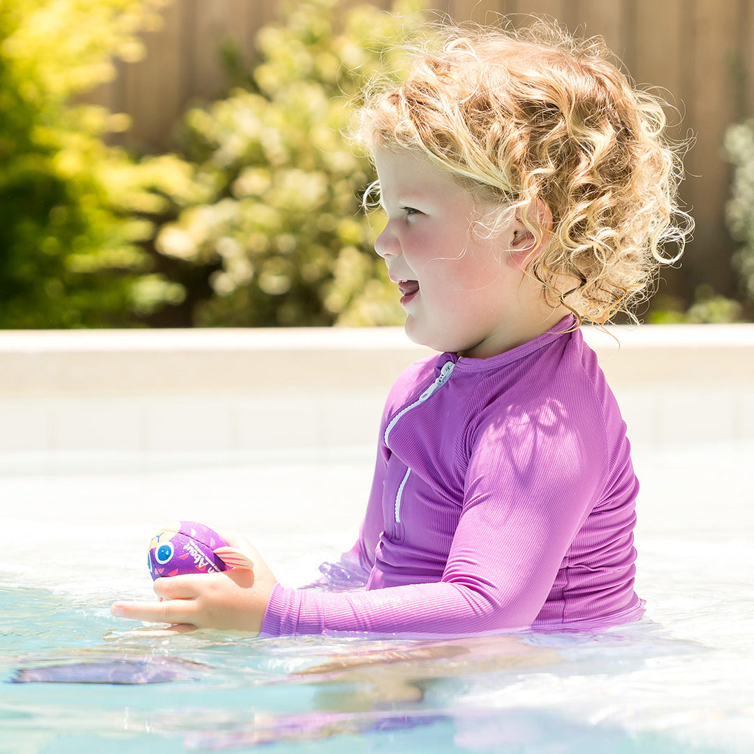 Little one wearing UV protective long sleeve rash top in lilac.