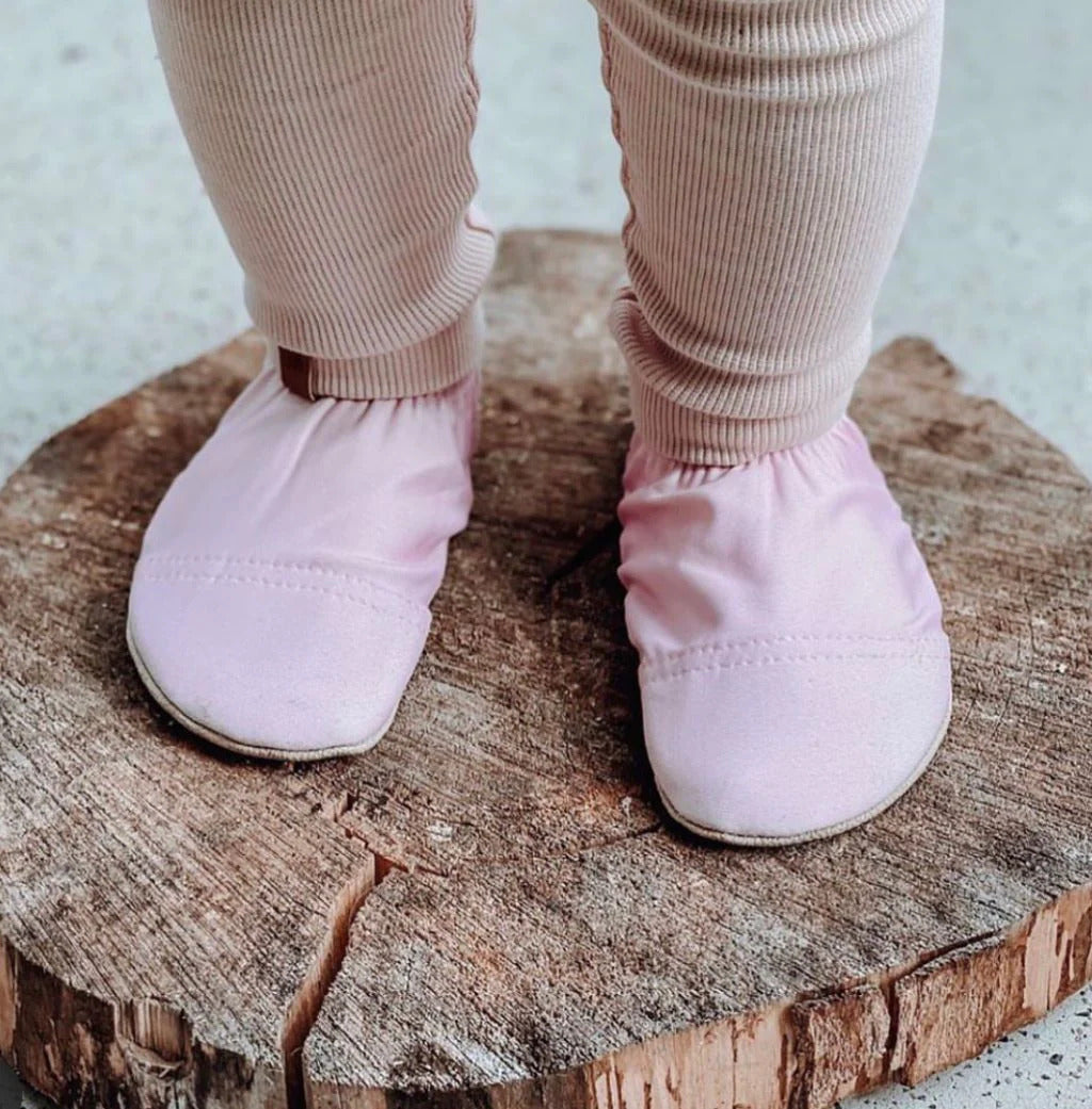 Lifestyle image of little one wearing pale pink non-slip shoes for beach, pool and home.