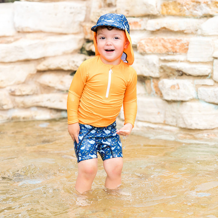 Child wearing neoprene swim shorts in navy and sharks themed print.