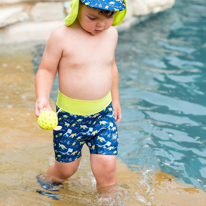 Child wearing neoprene swim shorts in navy and turtles and mantrays themed print.