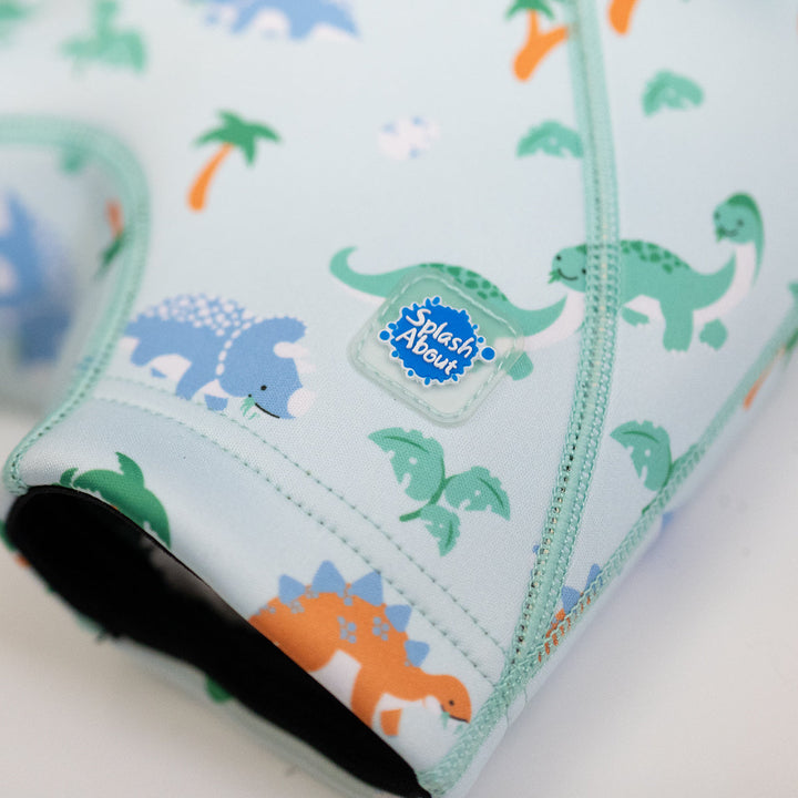 Close up of neoprene swim shorts in mint and dinosaurs themed print.
