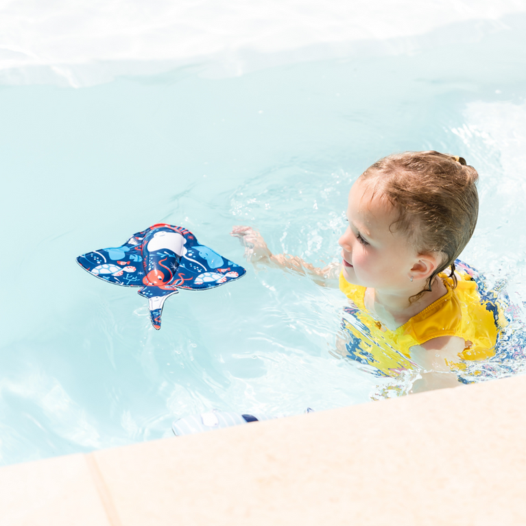 Kid playing with stingray in the pool