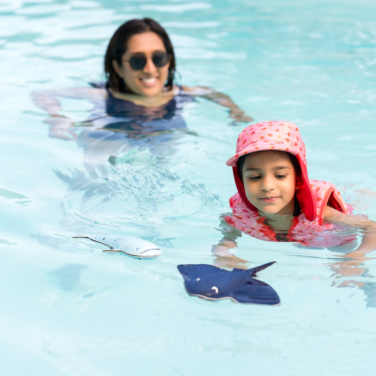 Kid playing with stingray and whale toys in the pool