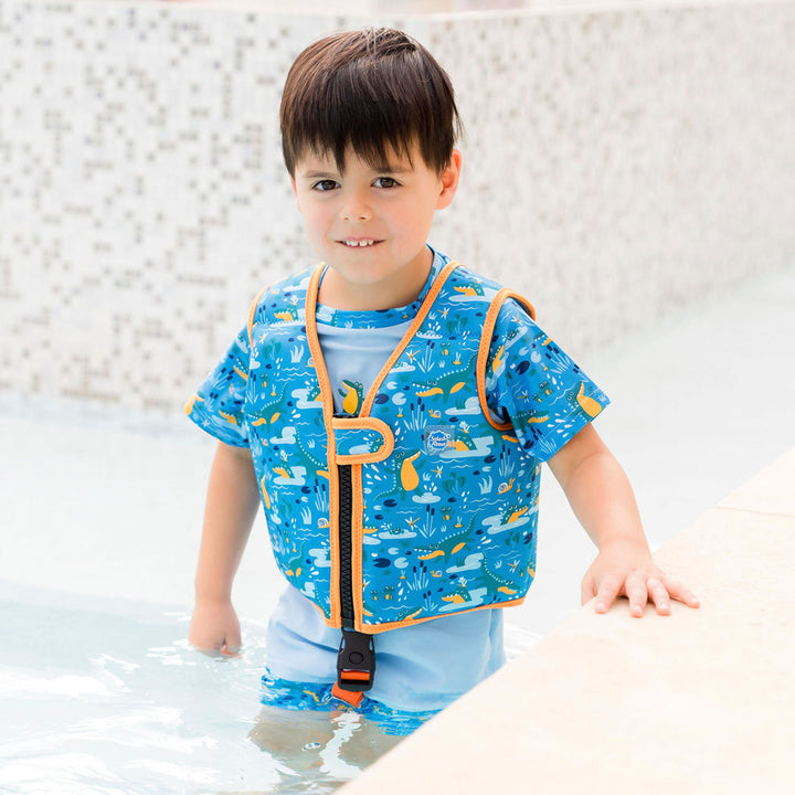 Little one wearing swim vest with non-removable floats in blue, bright orange trims, and crocodiles and frogs themed print. Open.