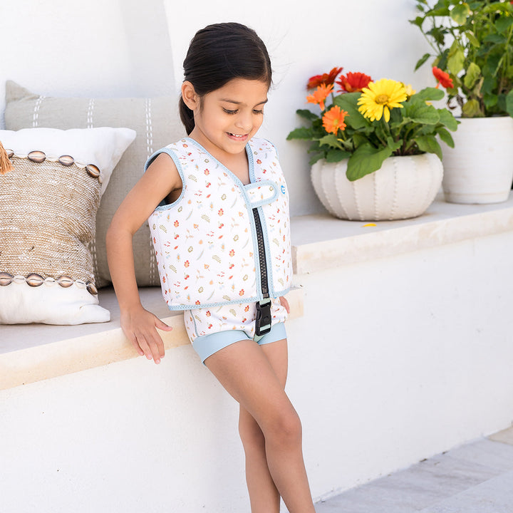 Lifestyle image of child wearing neoprene swim vest with non-removable floats in white, light blue trims, and Autumn themed print. Front.