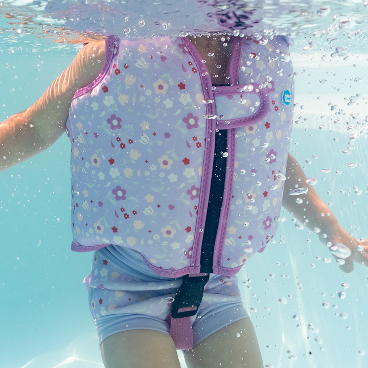 Lifestyle image of child swimming with neoprene swim vest with non-removable floats in lilac, and floral print.