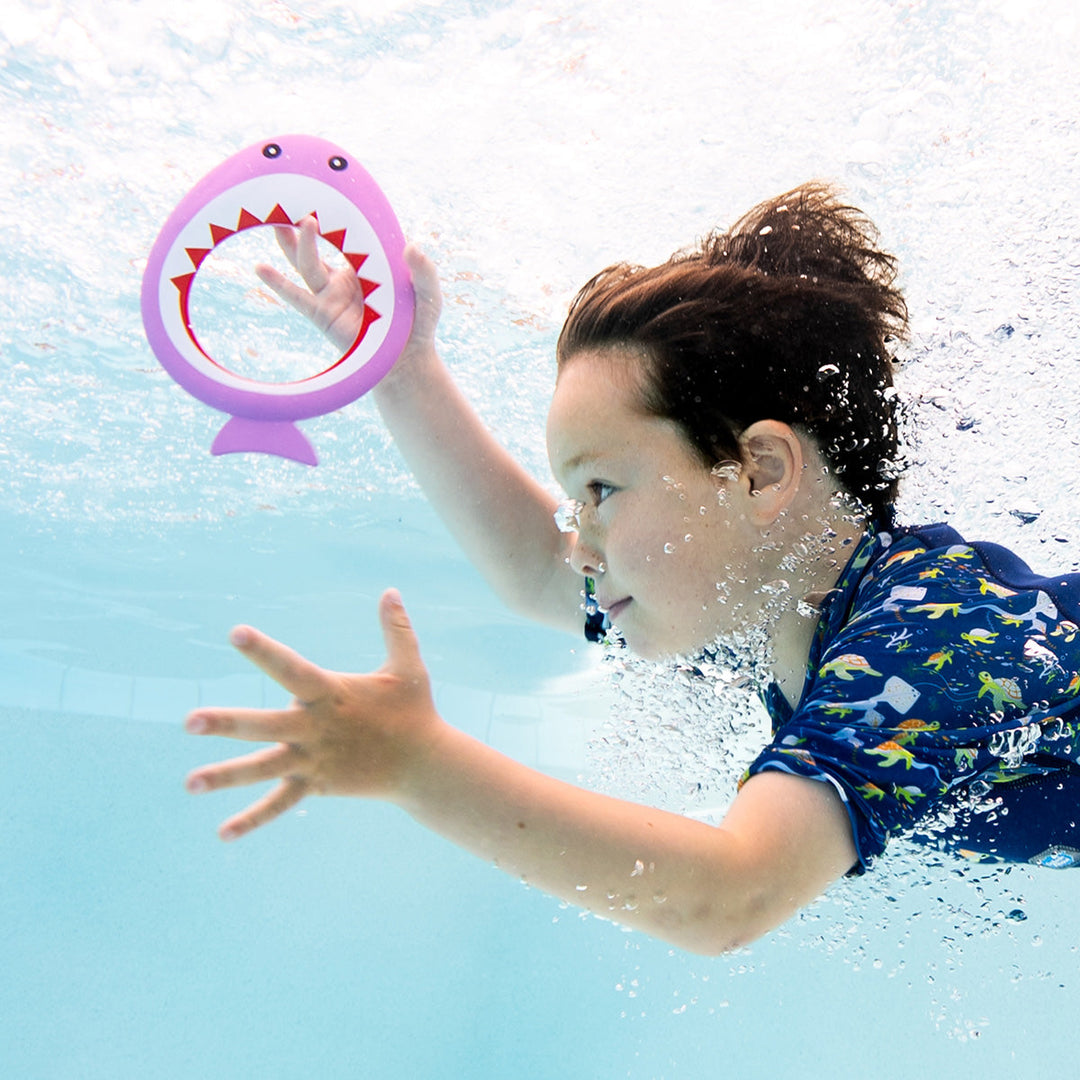 Kid playing with purple shark dive ring in the pool